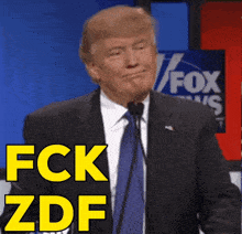 a man in a suit and tie stands in front of a microphone and says fck zdf