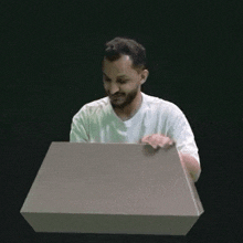 a man in a white shirt is sitting at a podium with a box in front of him