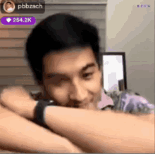 a man laying his head on his arm with a pbbzach icon in the background