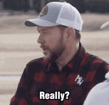 a man wearing a plaid shirt and a hat says " really "