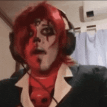 a man with red hair and face paint is wearing headphones and a suit .