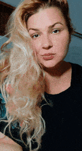 a woman with blonde hair and a black shirt looks at the camera