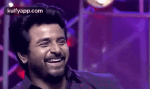 a man with a beard is laughing on a stage .
