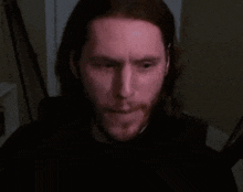 a man with long hair and a beard looks angry