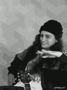 a black and white photo of a woman holding a guitar .