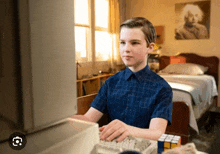 a young boy is typing on a keyboard in a bedroom
