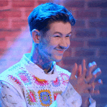 a man with a tattoo on his face is smiling and clapping his hands