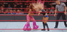 two women are wrestling in a wrestling ring while a referee looks on .