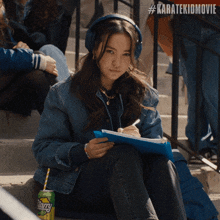 a woman wearing headphones sits on a set of stairs next to a can of stary soda