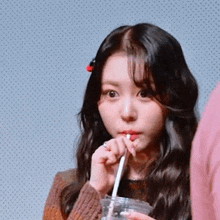 a young woman drinking through a straw from a plastic cup