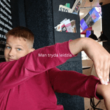 a boy in a pink shirt with the words man tryda leidzia written on his arm