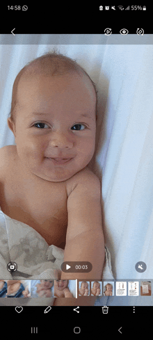 a baby laying on a bed with a play button on the bottom of the screen