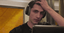 a young man wearing headphones is looking at a laptop