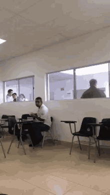 a man is sitting at a desk in a classroom with other students