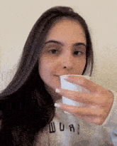 a woman wearing a sweatshirt that says ' abercrombie & fitch ' on it drinks from a white cup