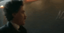 a man in a suit and tie is standing in a dark room in a room .