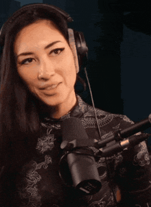 a woman wearing headphones is standing in front of a microphone that says ' ear ' on it