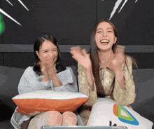 two women are sitting on a couch and one has a pillow that says ' i love you ' on it