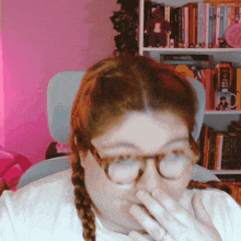 a woman wearing glasses is covering her mouth