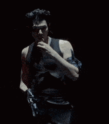 a man in a black vest is holding a gun in his hand