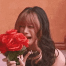 a woman is holding a bouquet of red roses in her hand and crying .