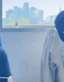a man wearing a mask is sitting in front of a window with a view of the city .