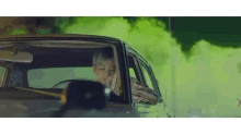 a woman is sitting in a car smoking a cigarette .