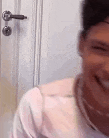 a man is smiling in front of a door with a key in it .