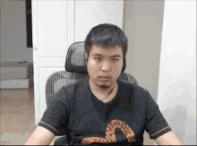 a man wearing headphones and a black shirt is sitting in an office chair .