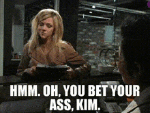 a woman sitting at a desk with the words " hmm oh you bet your ass kim " on the bottom