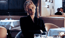 a woman is sitting at a table in a restaurant looking at the camera
