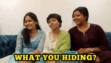 three women are sitting on a couch with the words " what you hiding " written above them