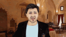 a man in a suit is making a funny face in front of a castle .