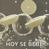 a row of shot glasses with slices of lime and the words hoy se bebe below