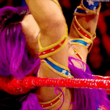 a woman with purple hair is standing in a wrestling ring .