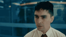 a man in a white shirt and red tie looks at something