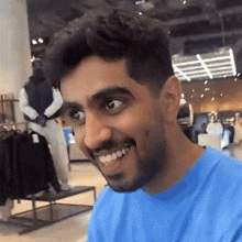 a man with a beard wearing a blue shirt is smiling in a clothing store .