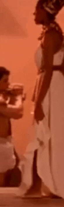 a woman in a white dress is kneeling down next to a man in a white shirt .