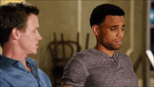 two men are sitting next to each other and one of them is wearing a grey shirt