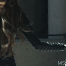 a woman with long blonde hair is wearing a black leather outfit with ms written on the bottom