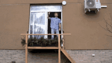a man stands on a balcony with an lg air conditioner hanging from the side of the building
