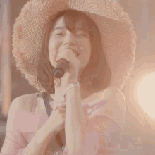 a woman wearing a straw hat is singing into a microphone .