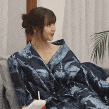 a woman in a blue robe is sitting on a chair