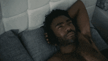 a shirtless man is laying on a bed with his hands behind his head