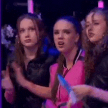 a group of young women are standing next to each other in a dark room and clapping .