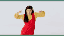 a woman in a red dress and a yellow sweater is dancing .