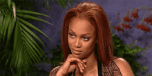 a woman with red hair is holding her hand to her chin .
