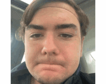 a man with a headband on his head is making a funny face in a car .