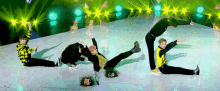 a group of young men are performing a dance on a stage with a green background .
