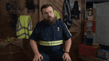 a man with glasses and a beard is sitting in front of a sign that says you found it